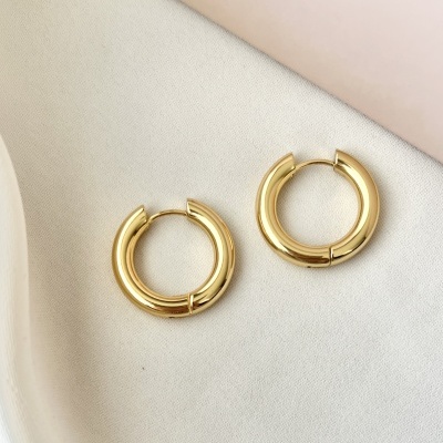 Brincos de argola dourados sobre tecido branco