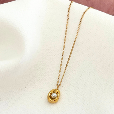 Colar dourado com pendente e pérola sobre tecido branco