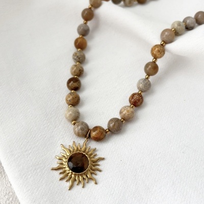 Colar de contas castanhas e creme com pendente dourado em forma de sol