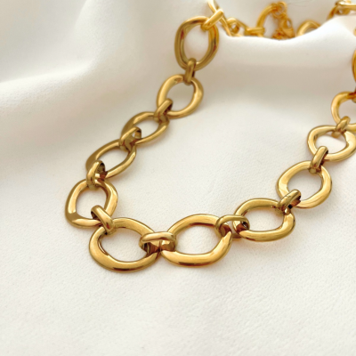 Colar de elos dourados sobre tecido branco