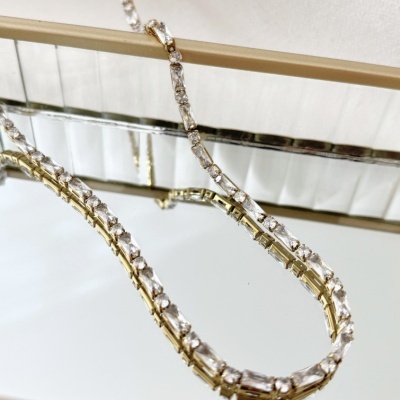 Colar dourado com pedras transparentes sobre espelho