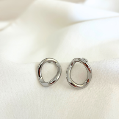Brincos prateados de design circular irregular sobre tecido branco