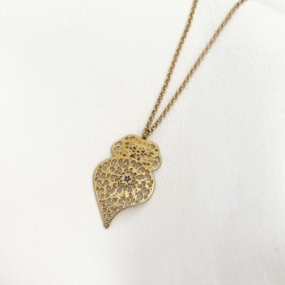 Colar dourado com pingente decorativo em forma de folhas sobre fundo branco