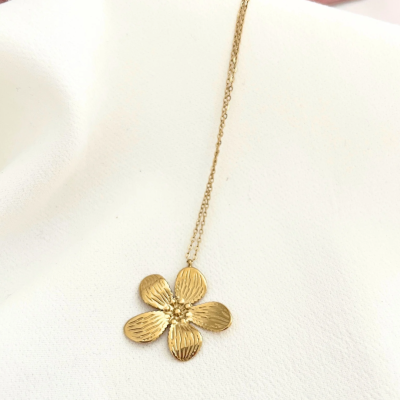 Colar dourado com pendente flor cinco pétalas sobre tecido branco