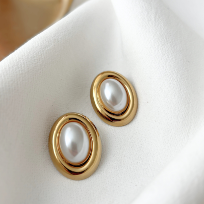 Botões dourados com pérolas sobre tecido branco