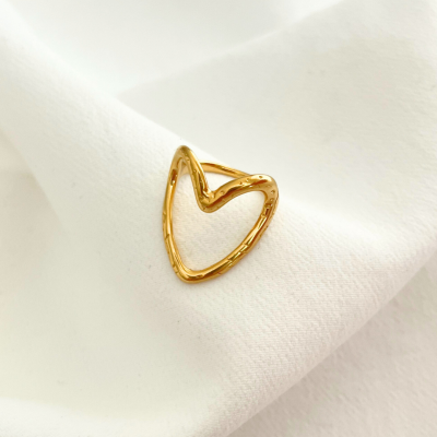 Anel dourado em forma de coração sobre tecido branco