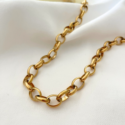 Colar dourado de elos ovais sobre tecido branco