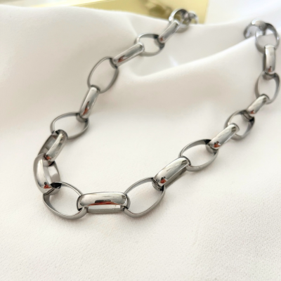 Colar de elos grandes de metal prateado sobre tecido branco