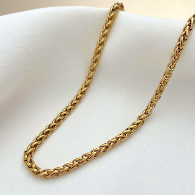 Colar dourado tipo corrente sobre tecido branco