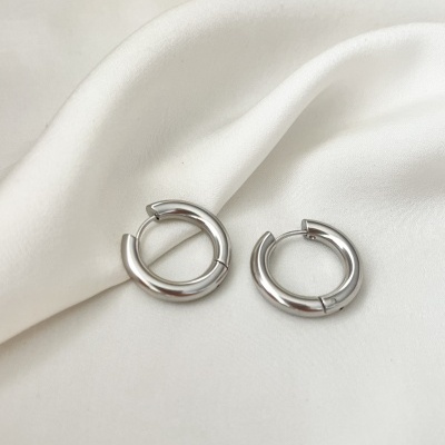 Brincos de argola prateados sobre tecido branco