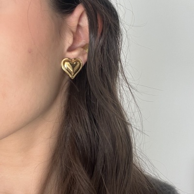 Brinco dourado em forma de coração na orelha