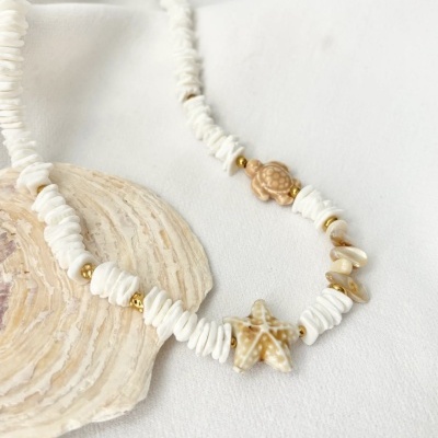 Colar com discos brancos, contas douradas, pendentes de estrela-do-mar e tartaruga em fundo branco