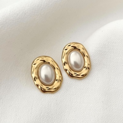 Brincos dourados com pedra de pérola sobre fundo branco