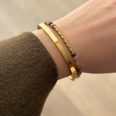 Pulseiras douradas e com contas no pulso de uma pessoa.