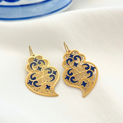 Brincos dourados com detalhes azuis sobre tecido branco