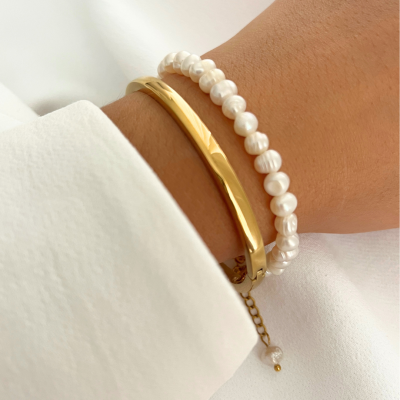 Pulseira de pérolas naturais e pulseira dourada lisa no pulso