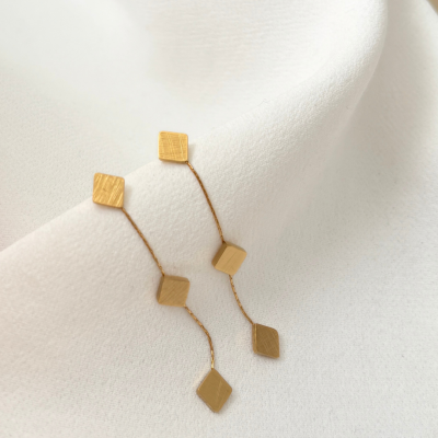 Brincos dourados com quadrados em tecido branco