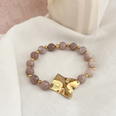 Pulseira com contas rosadas e elemento dourado de formato irregular