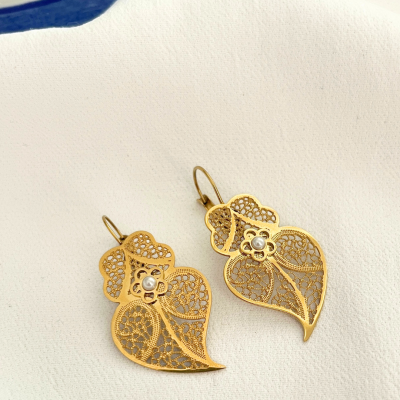 Brincos dourados em filigrana com pérola sobre tecido branco