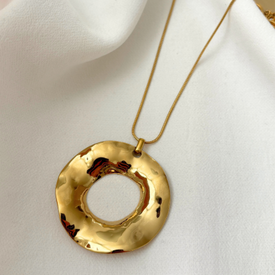 Colar com pendente redondo dourado sobre tecido branco