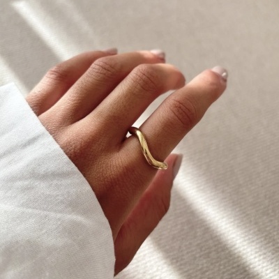 Mão com anel dourado ondulado no dedo indicador