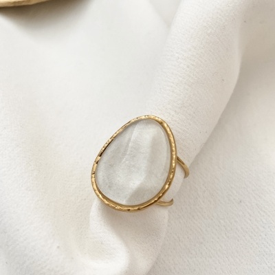 Anel dourado com vidro transparente em fundo branco de tecido