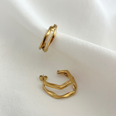 Brincos dourados entrelaçados sobre tecido branco