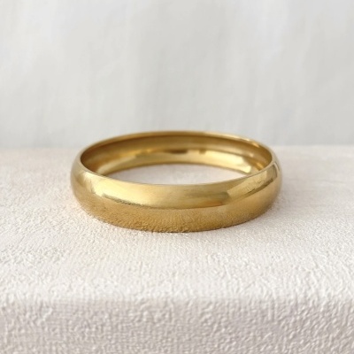 Aliança de ouro amarelo com acabamento brilhante sobre superfície clara texturizada