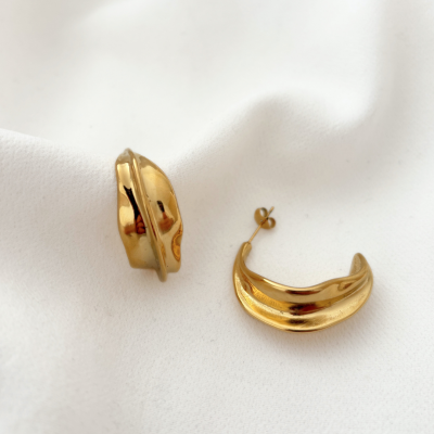 Brincos dourados curvos sobre tecido branco