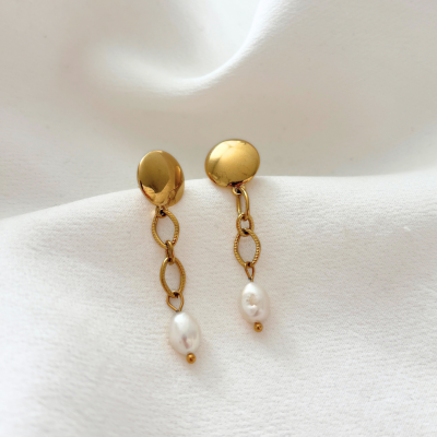 Brincos dourados com corrente e pérolas sobre tecido branco