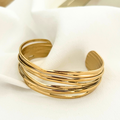 Pulseira dourada de metal com bandas entrelaçadas sobre tecido branco