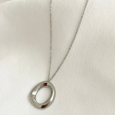 Colar com pingente oval irregular prateado sobre tecido branco