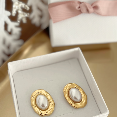 Brincos dourados com pérolas em caixa branca com laço rosa.