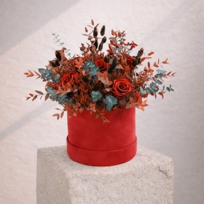 Arranjo floral em vaso vermelho sobre pedra clara