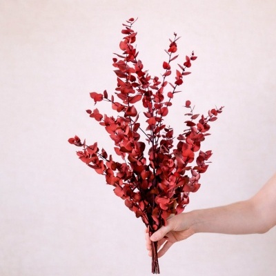 Ramo de flores artificiais vermelhas segurado por uma mão