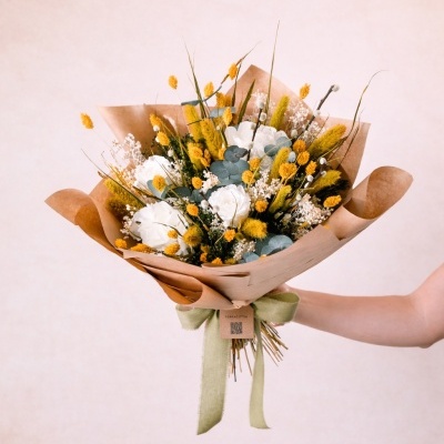 Buquê de flores preservadas brancas e amarelas em papel kraft com fita verde