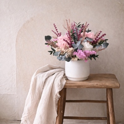 Arranjo floral em vaso branco sobre banco de madeira rústica com tecido branco
