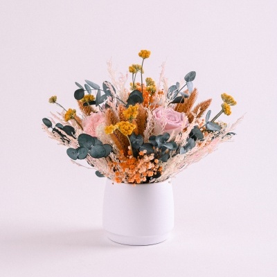Arranjo de flores secas em vaso branco com cores amarelas, rosas e castanhas
