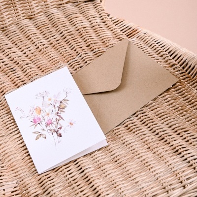 Cartão floral e envelope sobre cadeira de verga