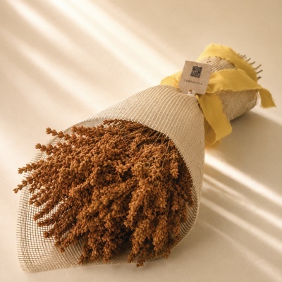 Bouquet de flores secas castanhas com embalagem em rede bege e fita amarelo-ocre