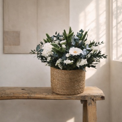 Arranjo floral em cesto de palha sobre banco de madeira rústica