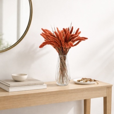 Consola de madeira clara com vaso de flores secas laranja e objetos decorativos