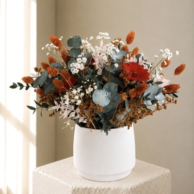 Arranjo floral em vaso branco sobre pedestal bege