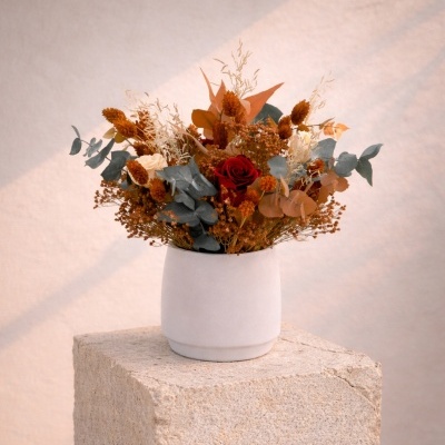 Arranjo floral seco em vaso branco sobre pedra