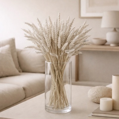 Arranjo de espigas de trigo secas em vaso de vidro sobre mesa com decoração minimalista