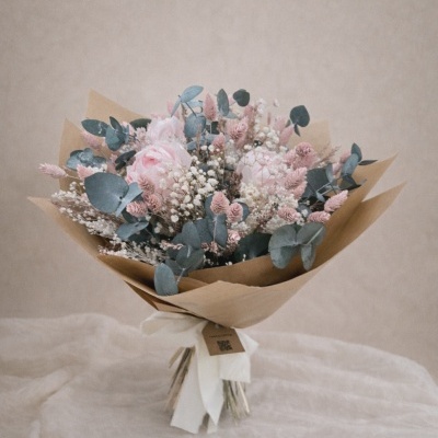 Buquê de flores cor-de-rosa, brancas e verde-acinzentadas em papel kraft