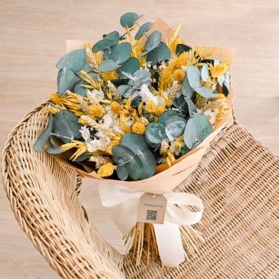 Bouquet de flores secas com folhas verdes e flores amarelas e brancas em cadeira de verga