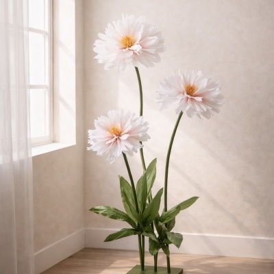 Escultura decorativa de flores cor-de-rosa claro com folhas verdes numa base verde sobre chão de madeira próximo a janela.