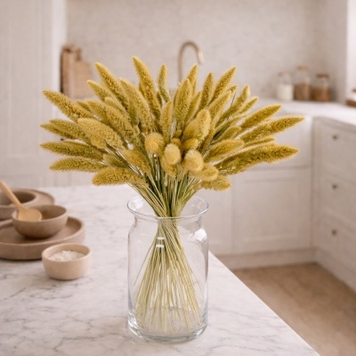 Vaso de vidro com flores secas amarelas num balcão de mármore numa cozinha branca.