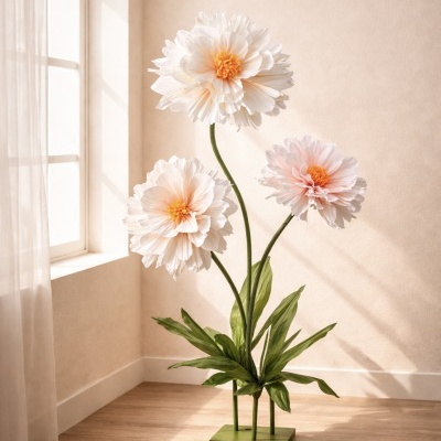 Escultura de flores artificiais grandes com folhas verdes em base verde, perto de janela e parede bege